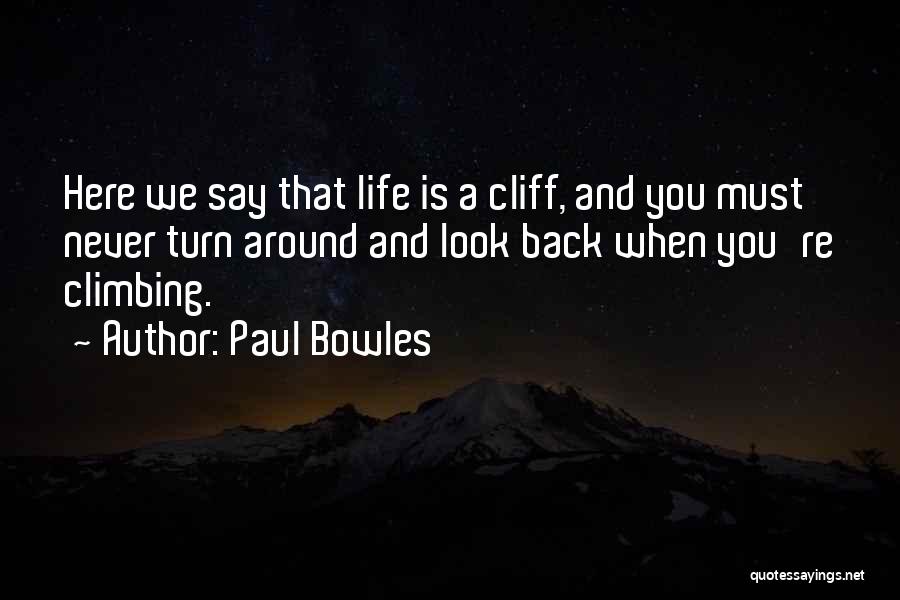 Paul Bowles Quotes: Here We Say That Life Is A Cliff, And You Must Never Turn Around And Look Back When You're Climbing.