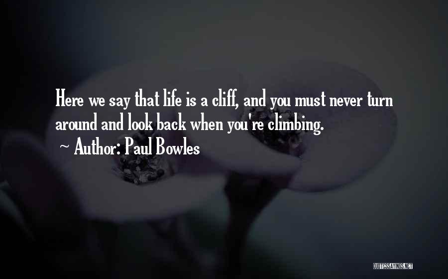 Paul Bowles Quotes: Here We Say That Life Is A Cliff, And You Must Never Turn Around And Look Back When You're Climbing.