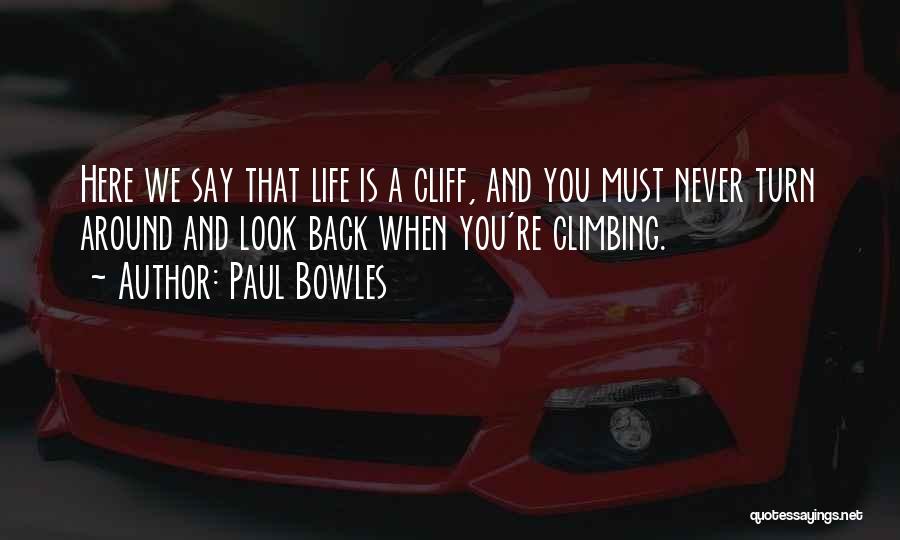 Paul Bowles Quotes: Here We Say That Life Is A Cliff, And You Must Never Turn Around And Look Back When You're Climbing.