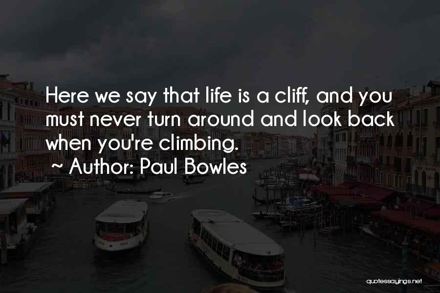 Paul Bowles Quotes: Here We Say That Life Is A Cliff, And You Must Never Turn Around And Look Back When You're Climbing.
