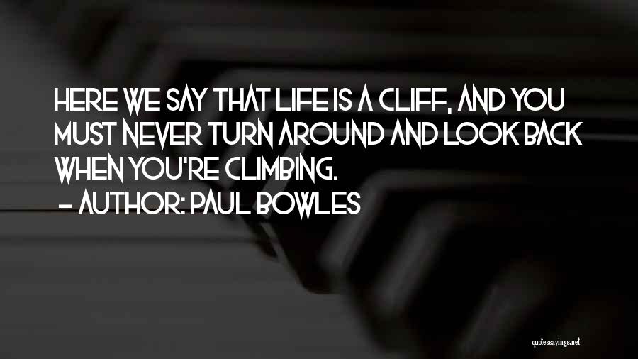 Paul Bowles Quotes: Here We Say That Life Is A Cliff, And You Must Never Turn Around And Look Back When You're Climbing.