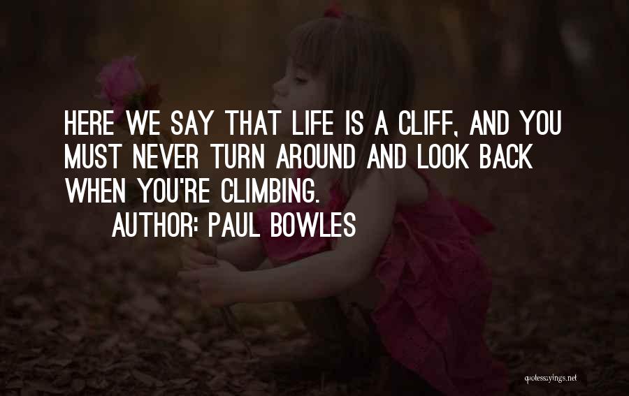 Paul Bowles Quotes: Here We Say That Life Is A Cliff, And You Must Never Turn Around And Look Back When You're Climbing.