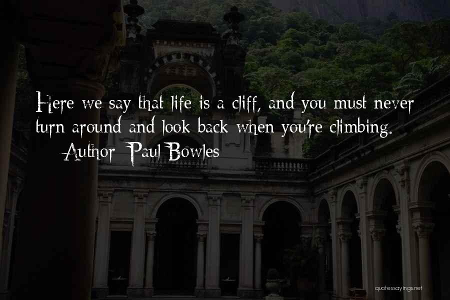 Paul Bowles Quotes: Here We Say That Life Is A Cliff, And You Must Never Turn Around And Look Back When You're Climbing.