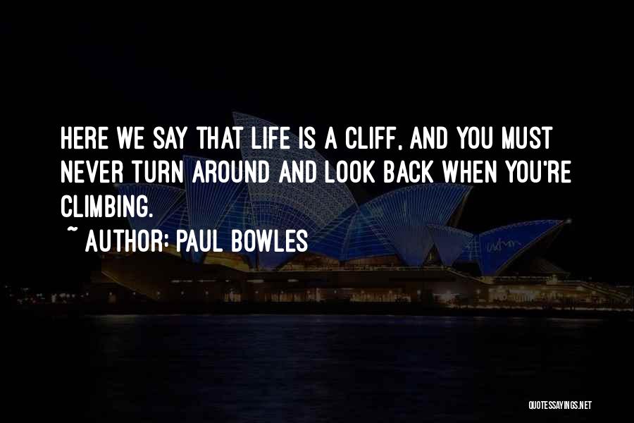 Paul Bowles Quotes: Here We Say That Life Is A Cliff, And You Must Never Turn Around And Look Back When You're Climbing.